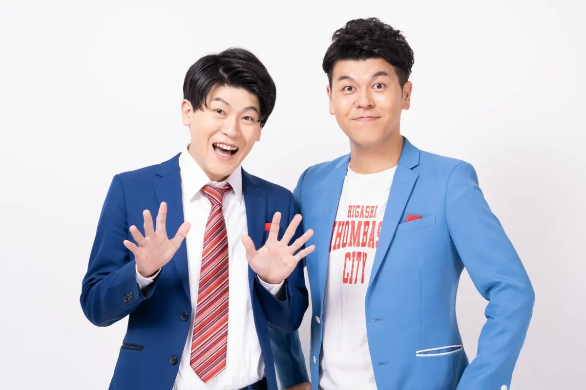 白い背景の前で笑顔を見せる2人組の男性