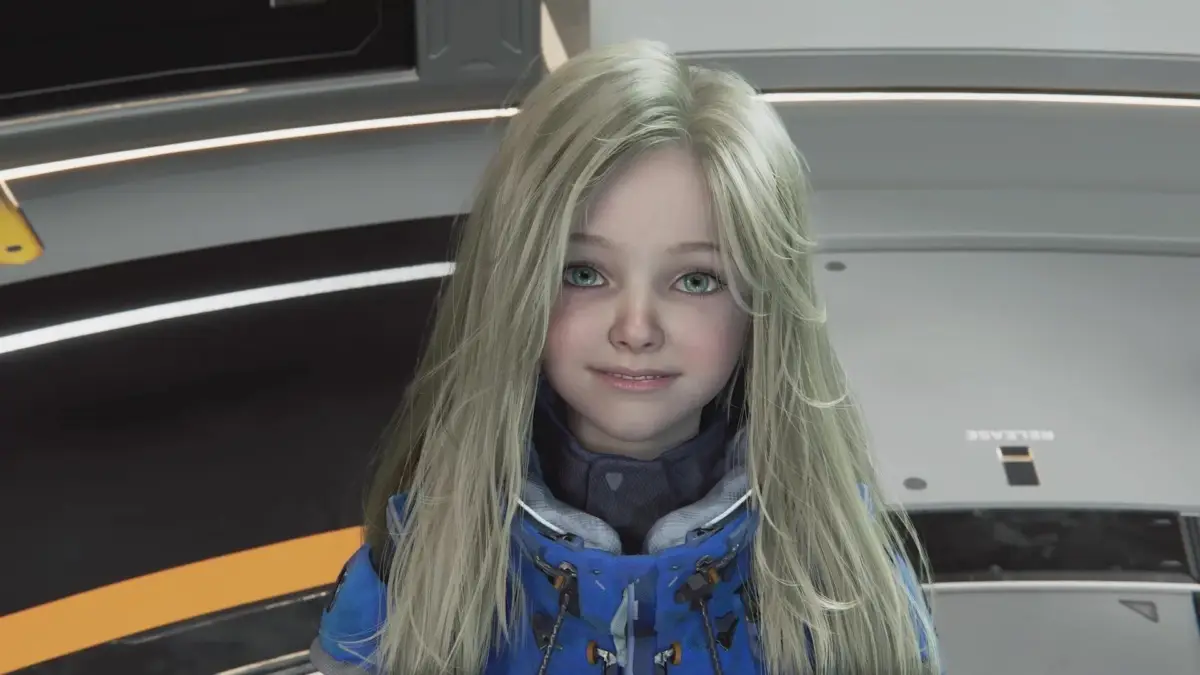 金髪と緑の目を持つ幼い少女が青いハイテクなジャケットを着用し微笑む