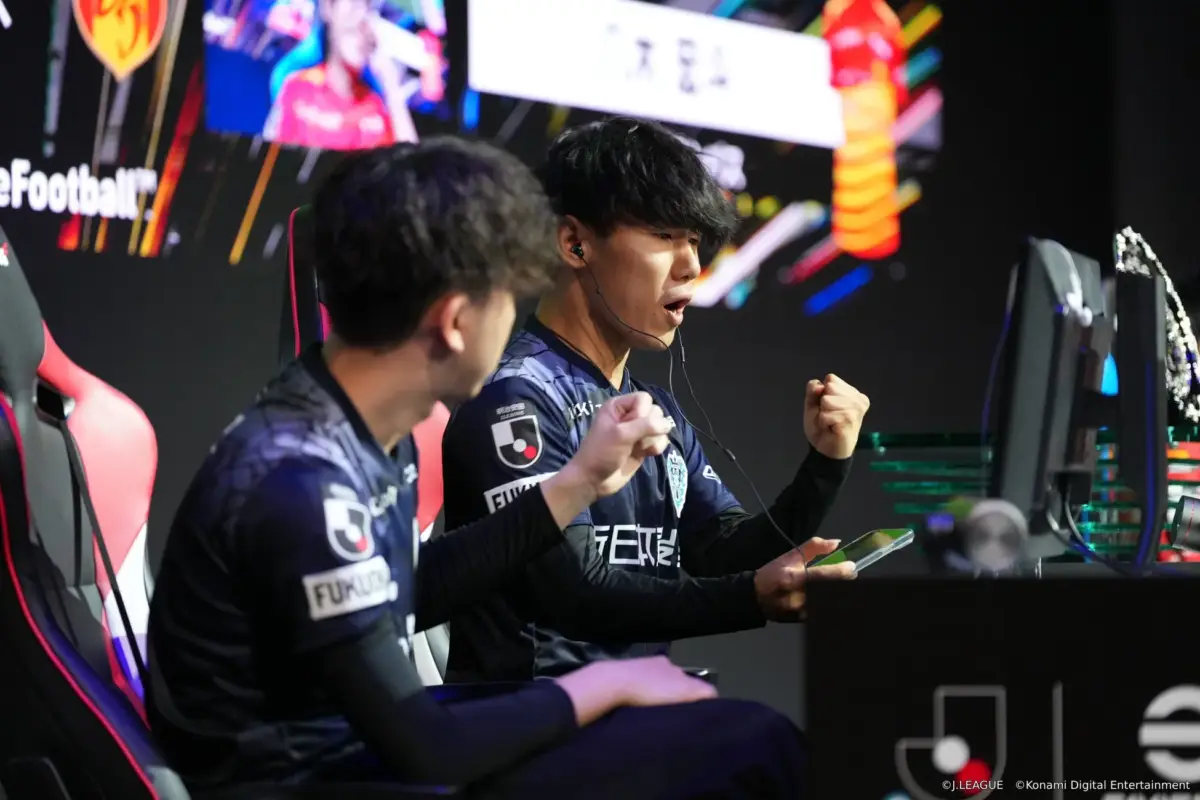 eスポーツの試合中に、Jリーグのユニフォームを着た選手がモニターに向かい、両手を握りしめ興奮している様子。