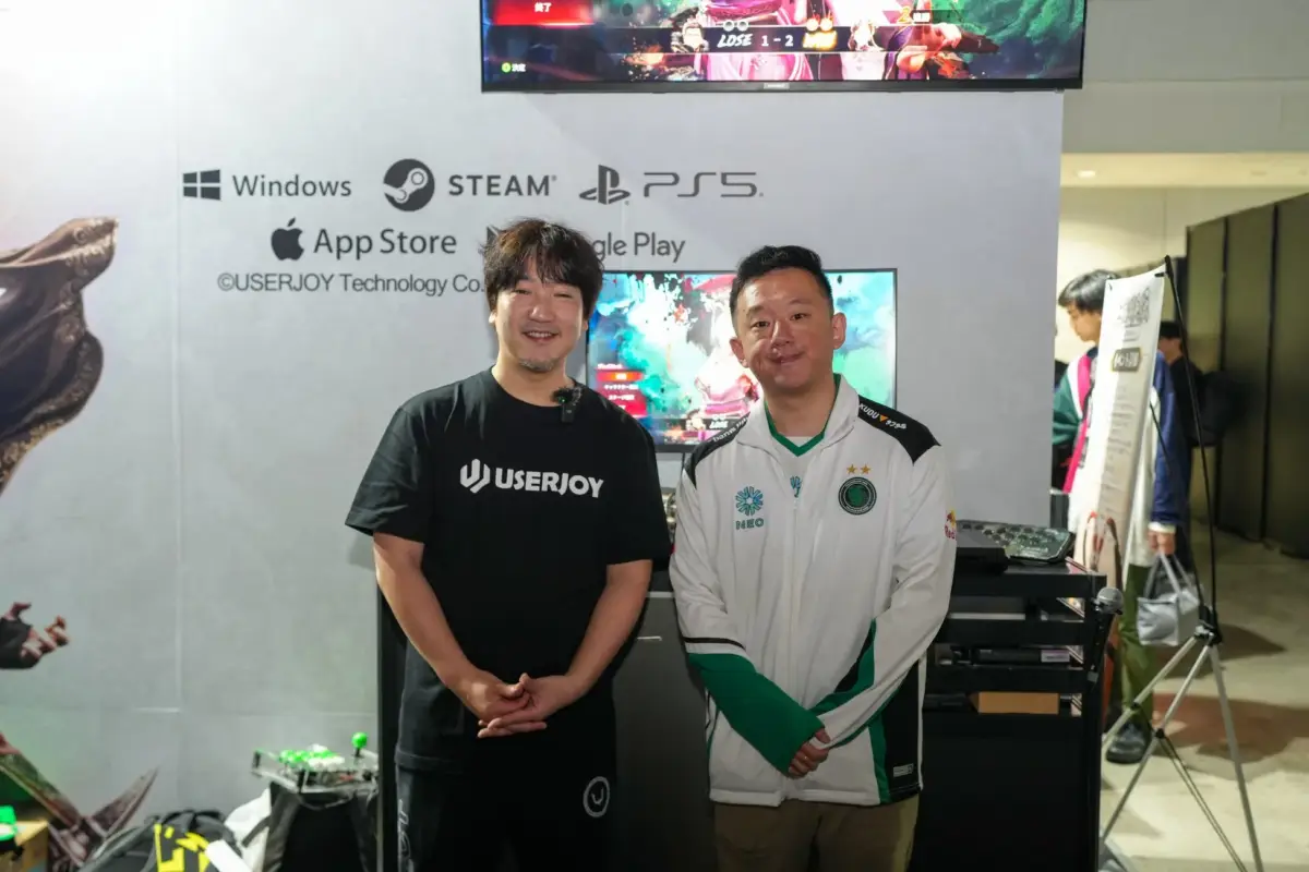 ゲームイベントのブースで開発者と思われる男性2人が写っている画像