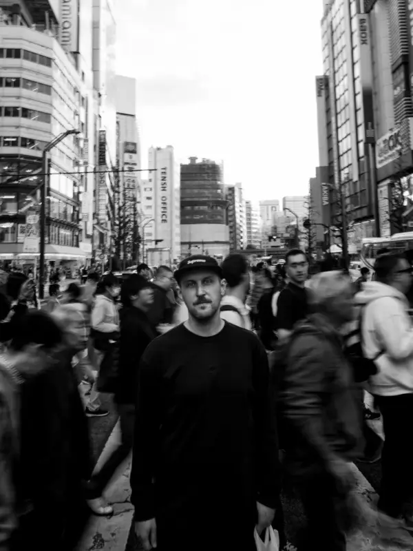 賑やかな都市の通りで立ち止まっている男性のモノクロ写真